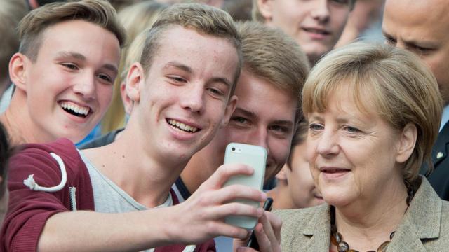 Bundeskanzlerin Angela Merkel (CDU) besucht am 30.09.2014 die Prälat-Diehl-Schule in Groß-Gerau (Hessen). Dabei posiert sie auf dem Schulhof zusammen mit Schülerinnen und Schülern für "Selfie"-Fotos.