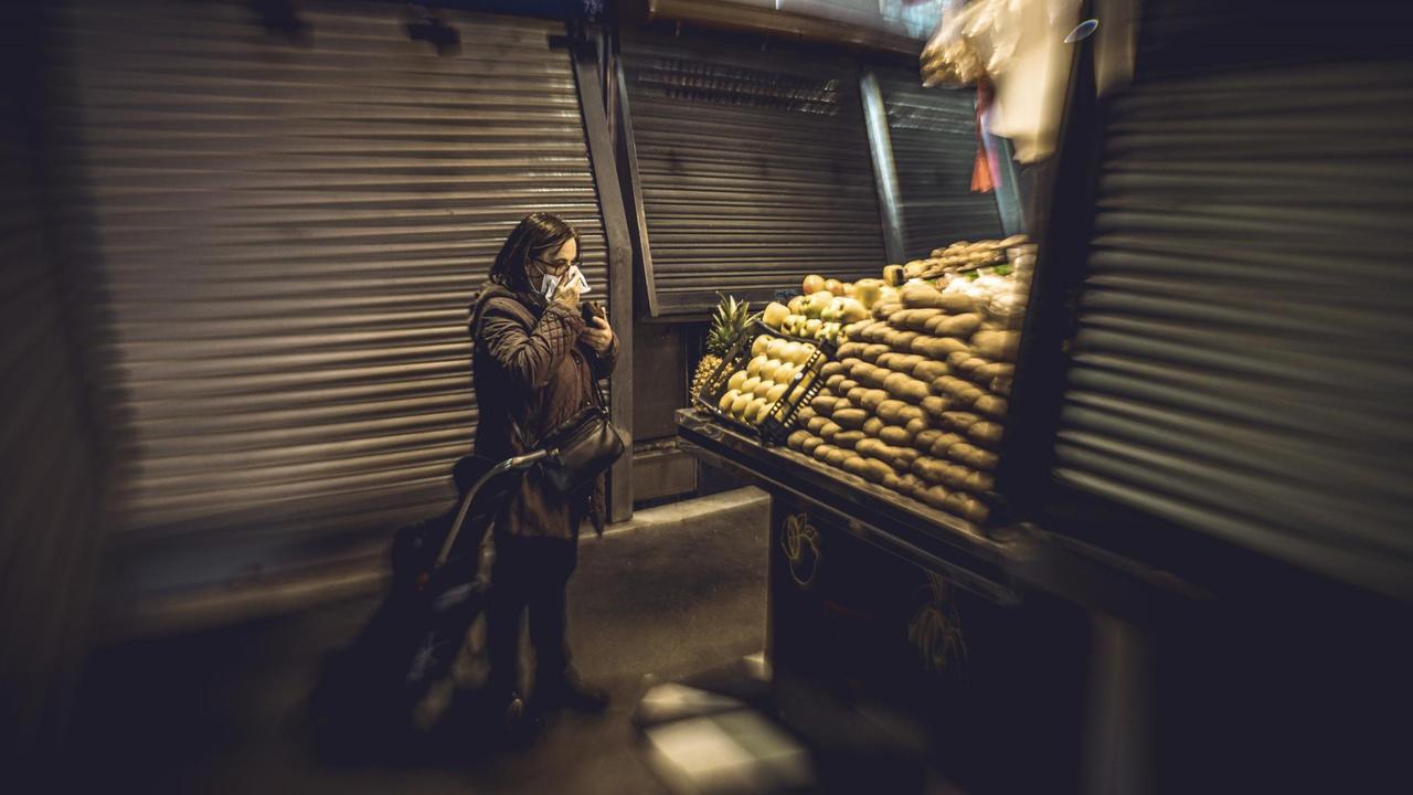 Eine Frau mit Atemmaske steht alleine auf dem Markt "La Boqueria" in Barcelona. Eine Frau mit Atemmaske steht alleine auf dem Markt "La Boqueria" in Barcelona.
