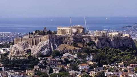 Sicht auf die Akropolis in der griechischen Hauptstadt Athen vom Hügel Lycabettus aus, im Hintergrund das Meer.