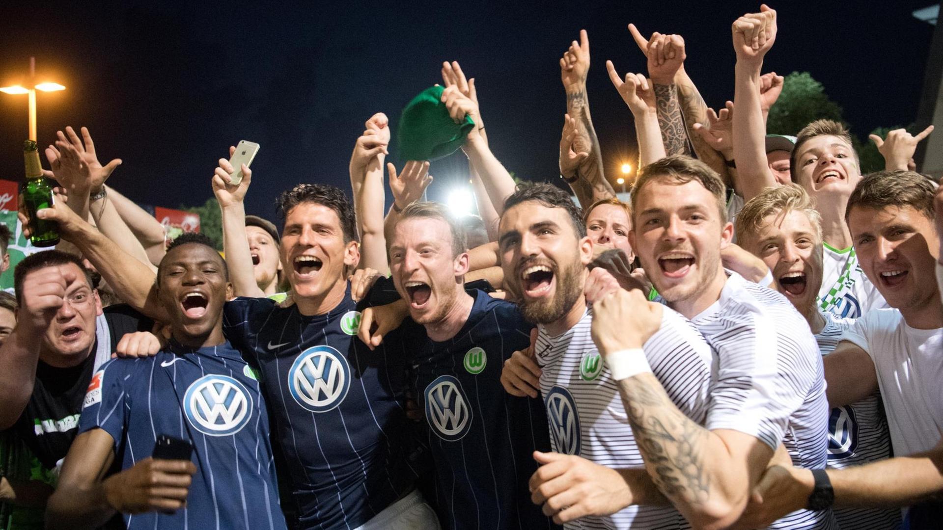 Die Wolfsburger Mannschaft feiert an einem Hinterausgang des Stadions mit den mitgereisten Fans den Klassenerhalt. Die Wolfsburger Mannschaft feiert an einem Hinterausgang des Stadions mit den mitgereisten Fans den Klassenerhalt.
