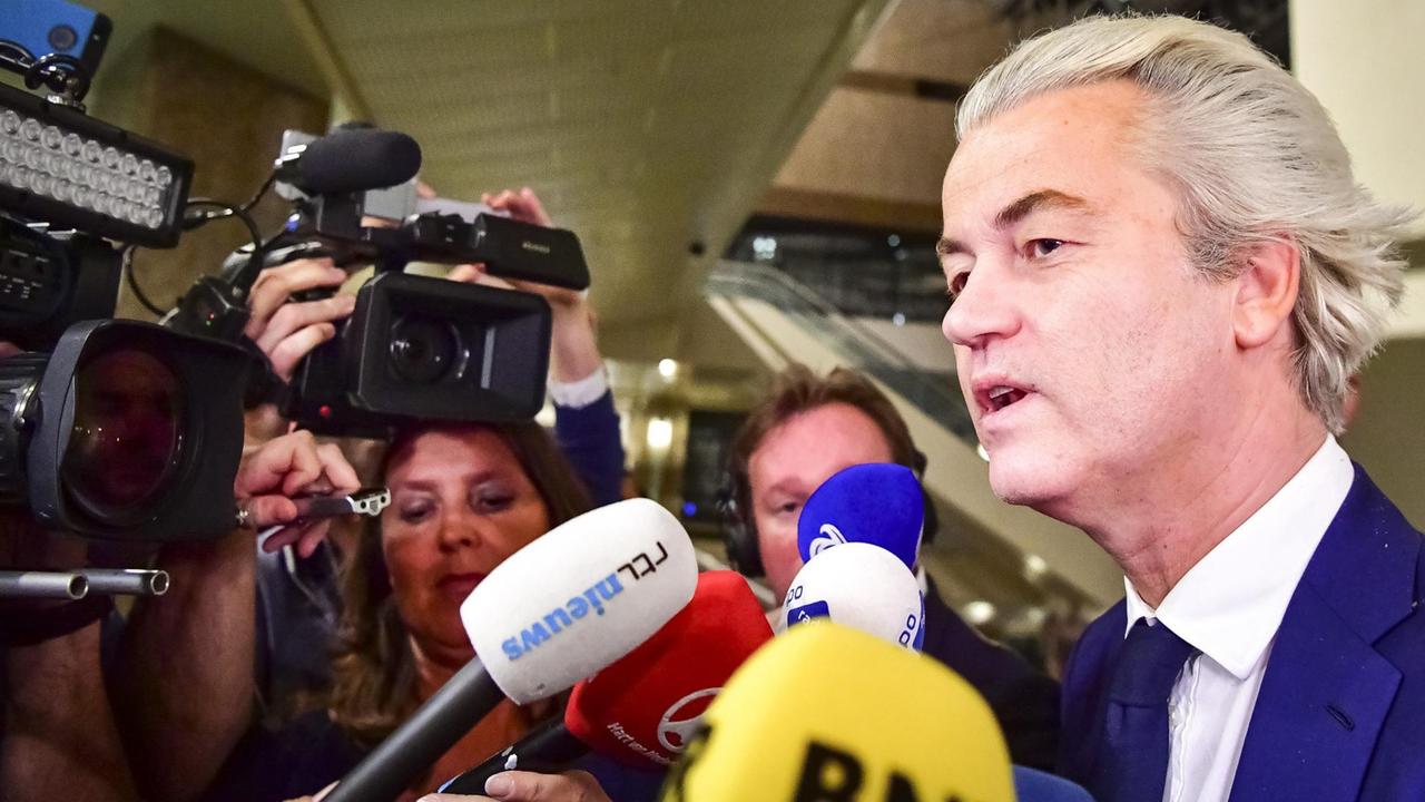 Geert Wilders spricht in der Wahlnacht in Den Haag mit Journalisten, vor ihm sind einige Mikrofone zu sehen.