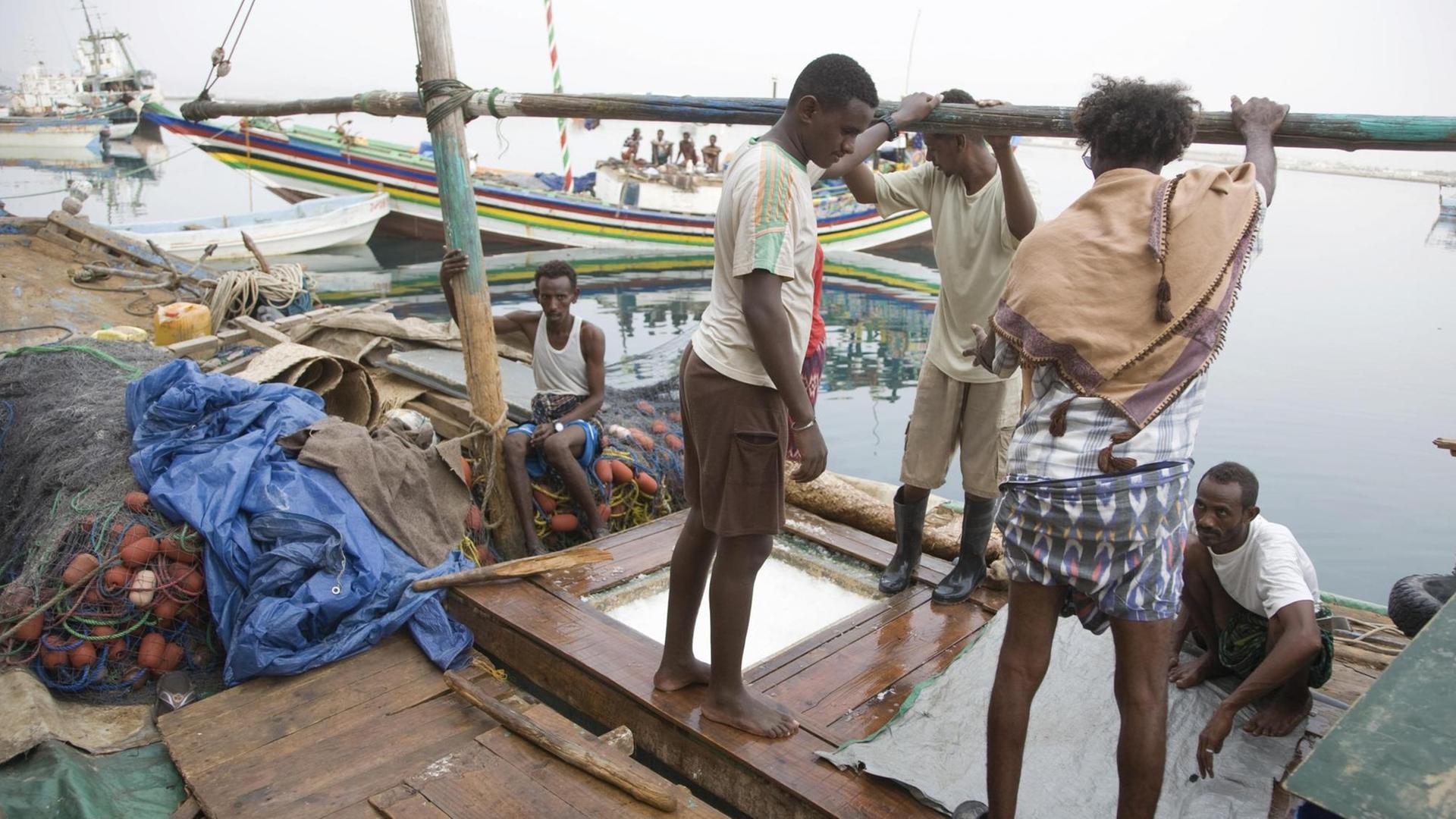 Arbeiter stehen an Deck eines Botes im Fischereihafen von Massawa, Eritrea Arbeiter stehen an Deck eines Botes im Fischereihafen von Massawa, Eritrea
