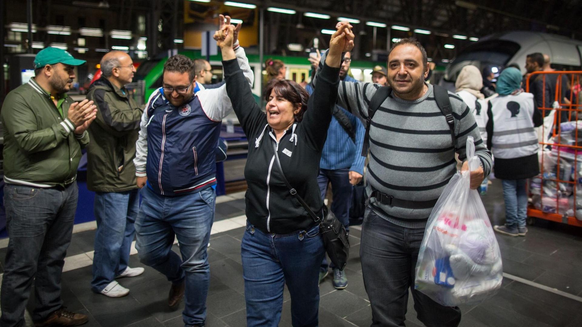 Flüchtlinge gehen am 2015 in Frankfurt am Main nach ihrer Ankunft im Hauptbahnhof durch ein Spalier von Menschen, die sie willkommen heißen. Flüchtlinge gehen am 2015 in Frankfurt am Main nach ihrer Ankunft im Hauptbahnhof durch ein Spalier von Menschen, die sie willkommen heißen.
