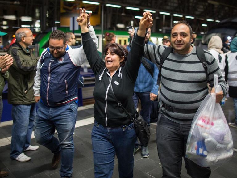 Flüchtlinge gehen am 2015 in Frankfurt am Main nach ihrer Ankunft im Hauptbahnhof durch ein Spalier von Menschen, die sie willkommen heißen.