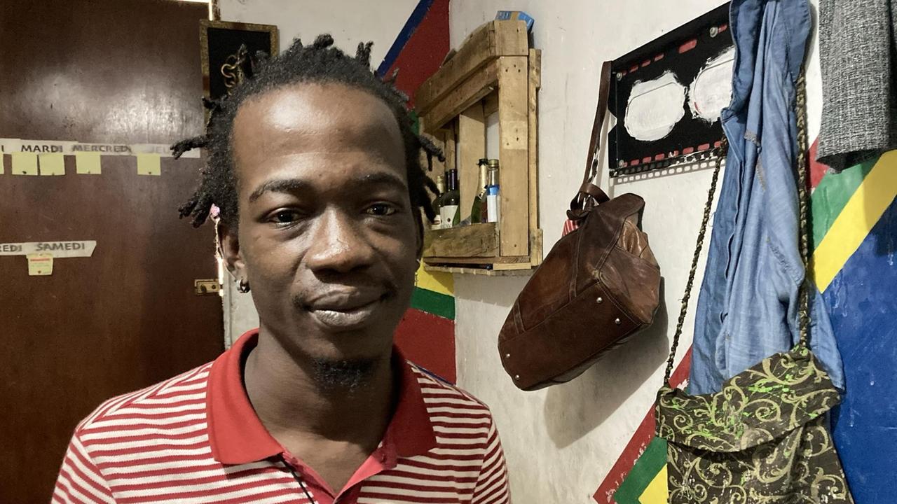 Ein junger Mann mit Rasta-Locken und rot-weiß gestreiftem T-Shirt steht in der Diele seiner Wohnung. Ein junger Mann mit Rasta-Locken und rot-weiß gestreiftem T-Shirt steht in der Diele seiner Wohnung.