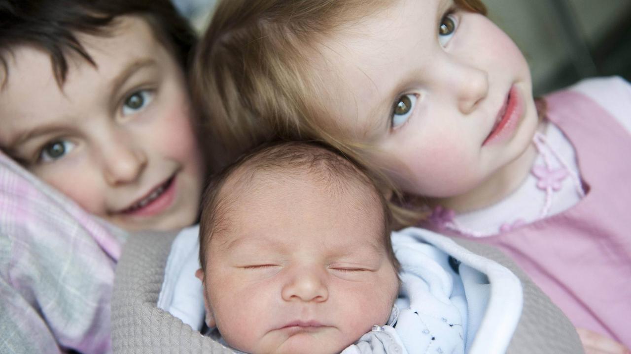 Ein Junge und ein Mädchen mit ihrem Geschwisterbaby Ein Junge und ein Mädchen mit ihrem Geschwisterbaby