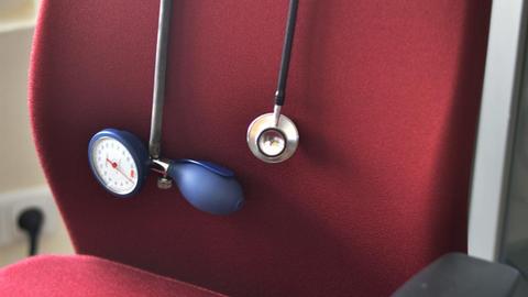 Ein Stethoskop hängt über einem Schreibtischstuhl in einer Hausarztpraxis.
