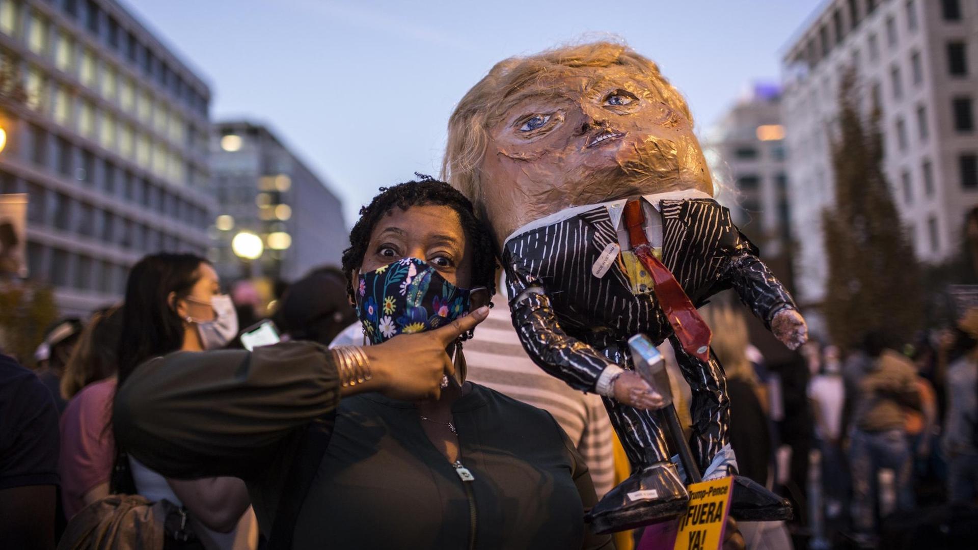 Eine schwarze Wählerin in Washington freut sich über das Ende der Präsidentschaft von Donald Trump und trägt eine Puppe des Noch-Präsidenten auf der Schulter. Eine schwarze Wählerin in Washington freut sich über das Ende der Präsidentschaft von Donald Trump und trägt eine Puppe des Noch-Präsidenten auf der Schulter.