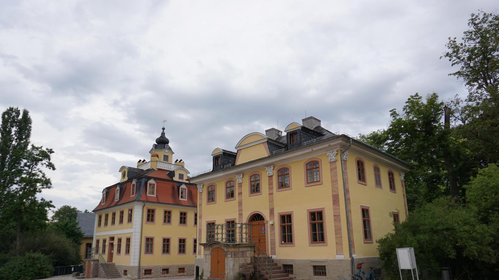 Ein barockes Schloß mit gelbem Anstrich und Treppenaufgang und Nebengebäude links.