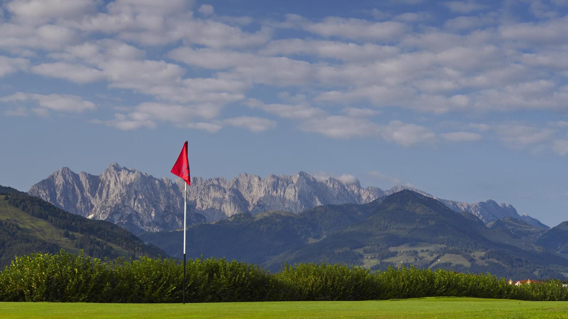 Der Rasen eines Golfplatzes vor der Kulisse der Alpen