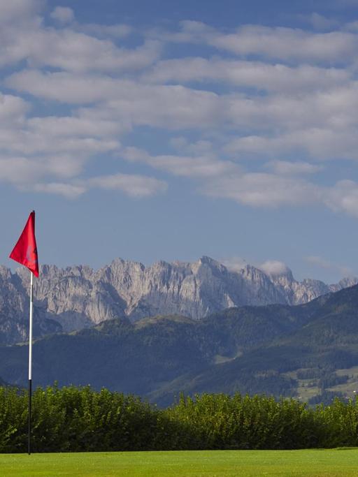 Der Rasen eines Golfplatzes vor der Kulisse der Alpen