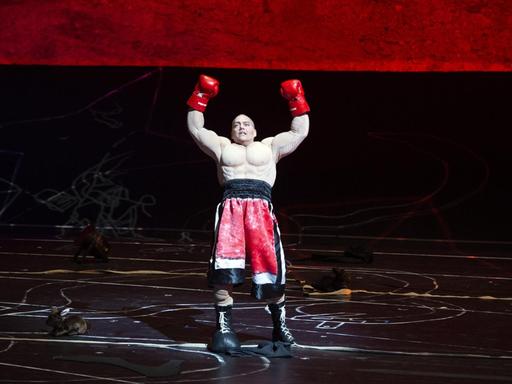 Zu sehen ist ein Boxer in Siegerpose auf der Bühne.