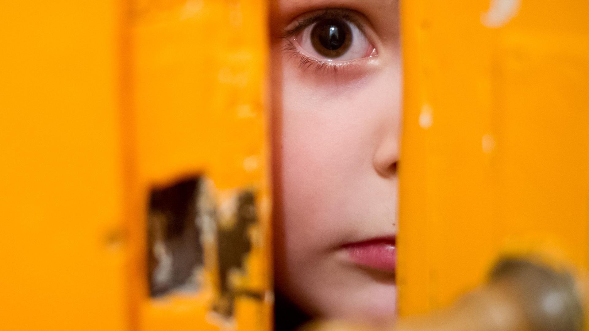 Ein junges Mädchen schaut am 24.01.2014 in Berlin durch einen Türschlitz. Ein junges Mädchen schaut am 24.01.2014 in Berlin durch einen Türschlitz.