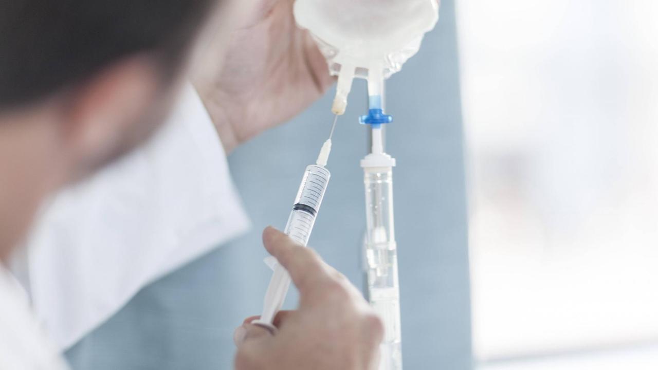 Ein Arzt füllt eine Infusion nach. Ein Arzt füllt eine Infusion nach.