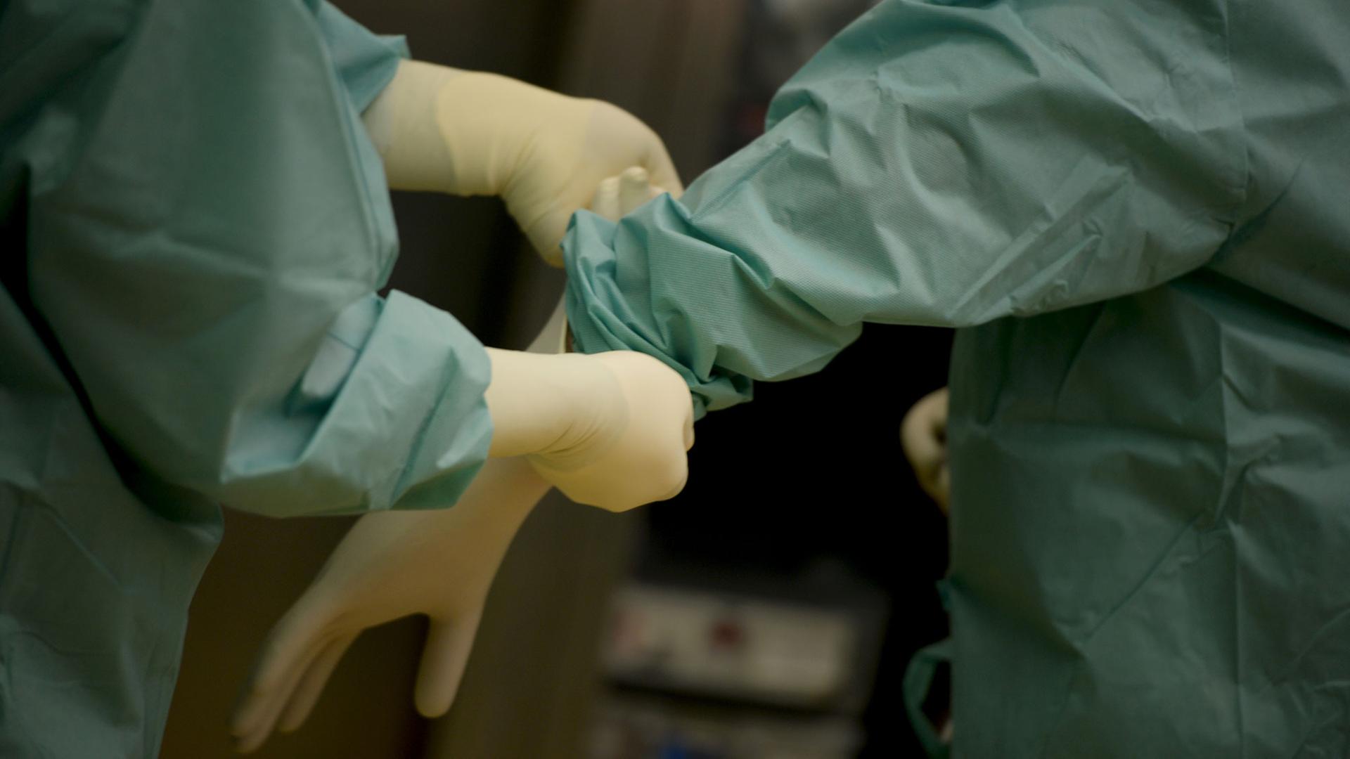 Ein Mediziner bekommt am 18.02.2014 in einer Klinik in Baden-Württemberg vor einer Operation ein Paar Handschuhe angezogen. Ein Mediziner bekommt am 18.02.2014 in einer Klinik in Baden-Württemberg vor einer Operation ein Paar Handschuhe angezogen.