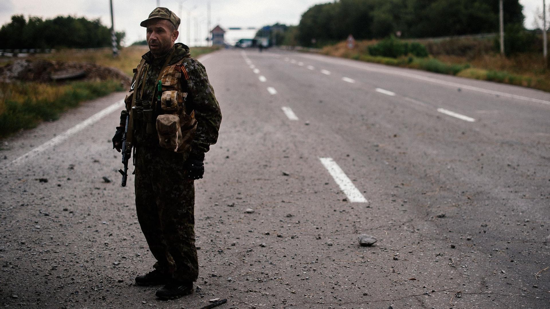 Ein prorussischer Soldat wacht nahe der ostukrainischen Stadt Donezk an einer Straße, auf der ein Flüchtlingskonvoi unterwegs war und beschossen wurde.