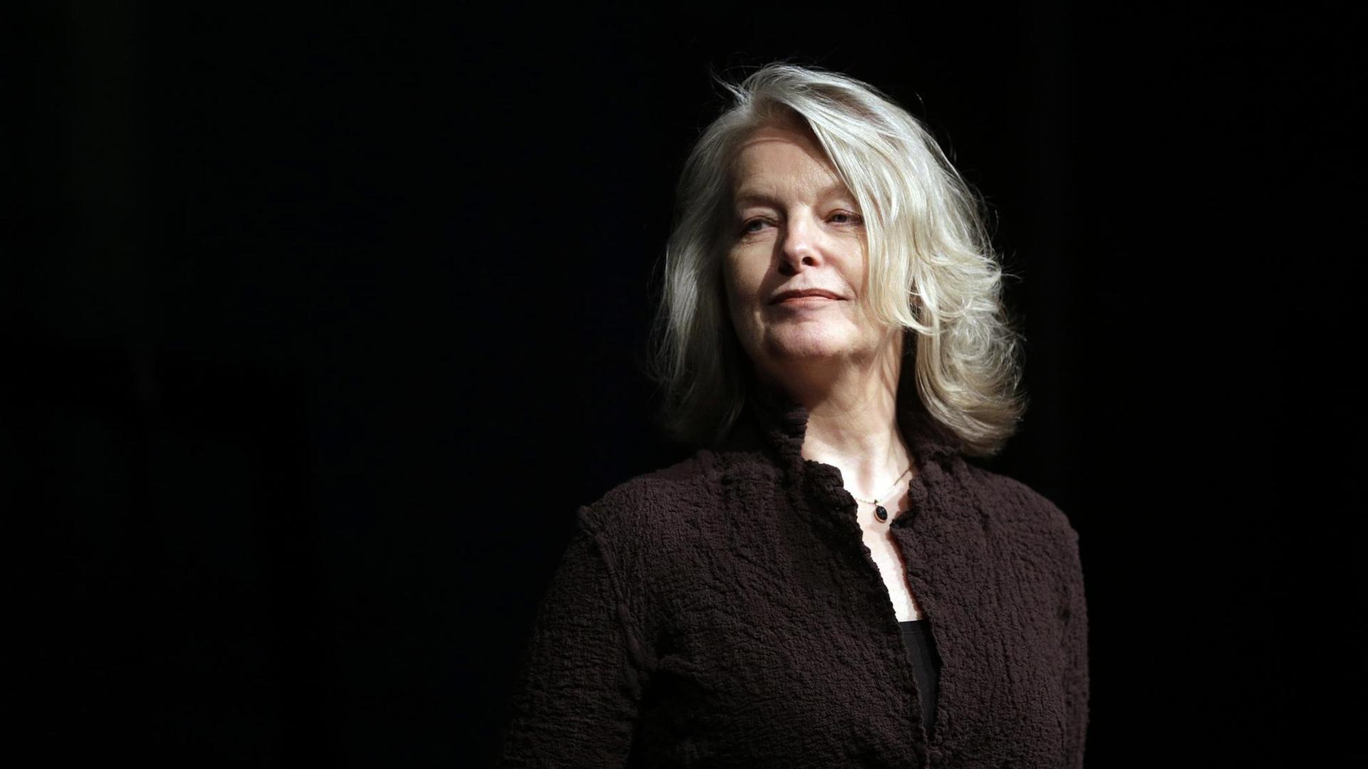 Marlene Streeruwitz steht vor einer schwarzen Wand und schaut stolz zur Seite. Marlene Streeruwitz steht vor einer schwarzen Wand und schaut stolz zur Seite.