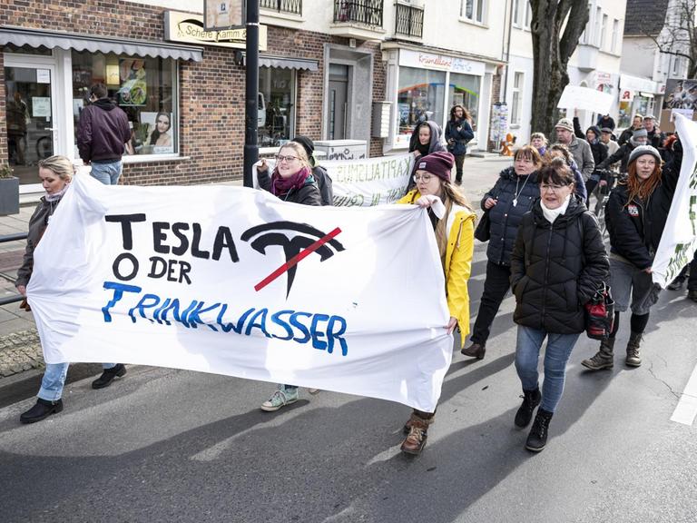 Demonstranten halten auf einer Demo gegen die geplante Tesla-Fabrik in Grünheide ein Banner mit der Aufschrift "Tesla oder Trinkwasser".