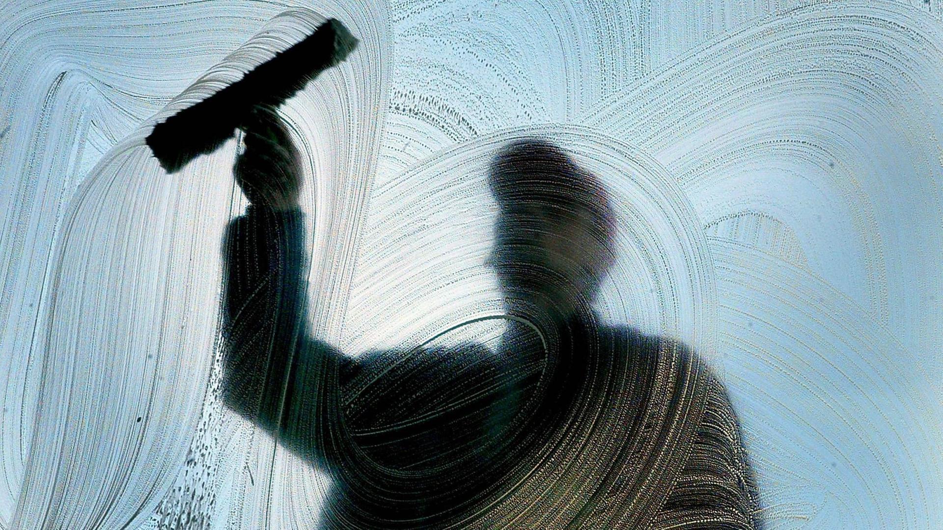 Silhouette eines Mannes, der Fenster putzt. Silhouette eines Mannes, der Fenster putzt.