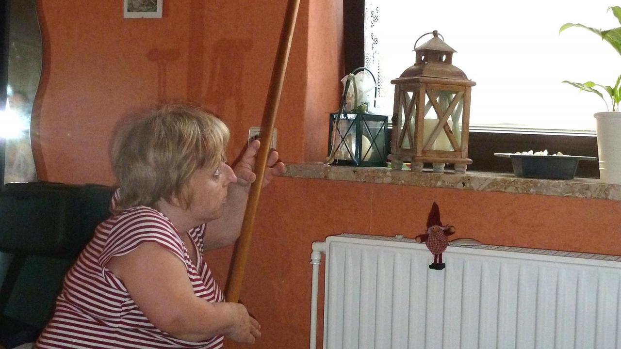 Eine kleine Frau öffnet und schließt mithilfe eines Stockes ein Fenster. Eine kleine Frau öffnet und schließt mithilfe eines Stockes ein Fenster.