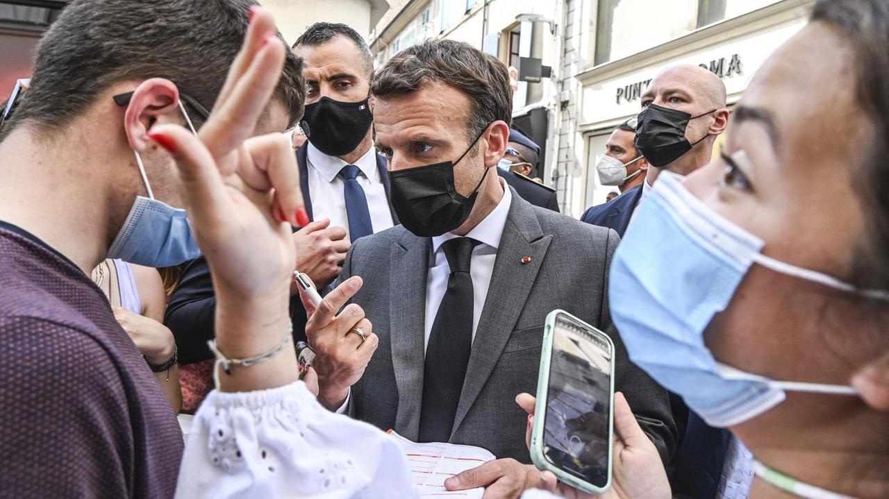 Der französische Präsident Macron ist beim Besuch eines kleinen Ortes im Südosten Frankreichs von Menschen umringt. Im Hintergrund befinden sich seine Leibwächter.