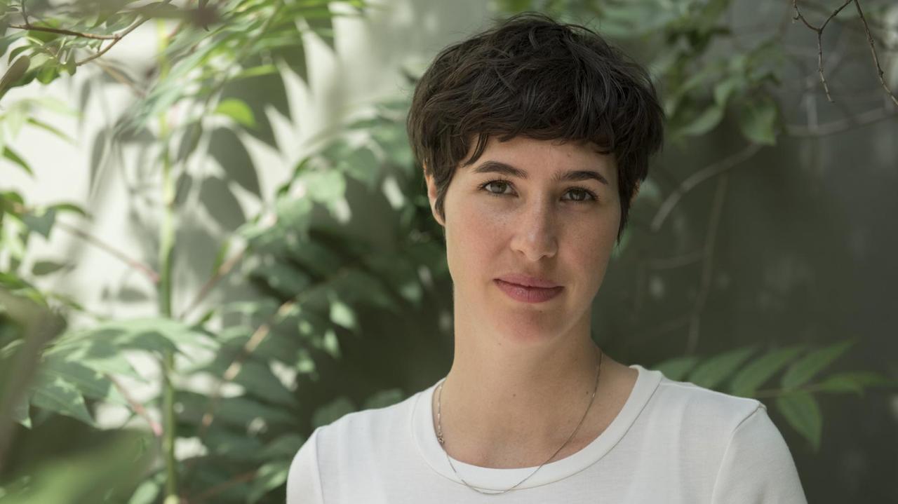 Porträt der Autorin und Journalistin Simone Rosa Miller vor grünem Blattwerk und einer sonnenbeschienenen Wand Porträt der Autorin und Journalistin Simone Rosa Miller vor grünem Blattwerk und einer sonnenbeschienenen Wand