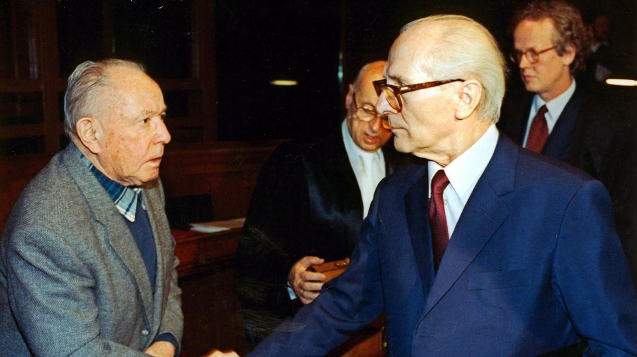 Der ehemalige DDR-Staatschef Erich Honecker (r) und der frühere Stasi-Chef Erich Mielke (l) verabschieden sich nach dem zweiten Prozess-Tag mit einem Händedruck. Der Honecker-Prozess wurde am 16. November 1992 im Kriminalgericht Moabit unter strengsten Sicherheitsvorkehrungen fortgesetzt. Honecker und Mielke müssen sich mit weiteren Mitangeklagten wegen der Todesschüsse an der innerdeutschen Grenze verantworten. Der ehemalige DDR-Staatschef Erich Honecker (r) und der frühere Stasi-Chef Erich Mielke (l) verabschieden sich nach dem zweiten Prozess-Tag mit einem Händedruck. Der Honecker-Prozess wurde am 16. November 1992 im Kriminalgericht Moabit unter strengsten Sicherheitsvorkehrungen fortgesetzt. Honecker und Mielke müssen sich mit weiteren Mitangeklagten wegen der Todesschüsse an der innerdeutschen Grenze verantworten.