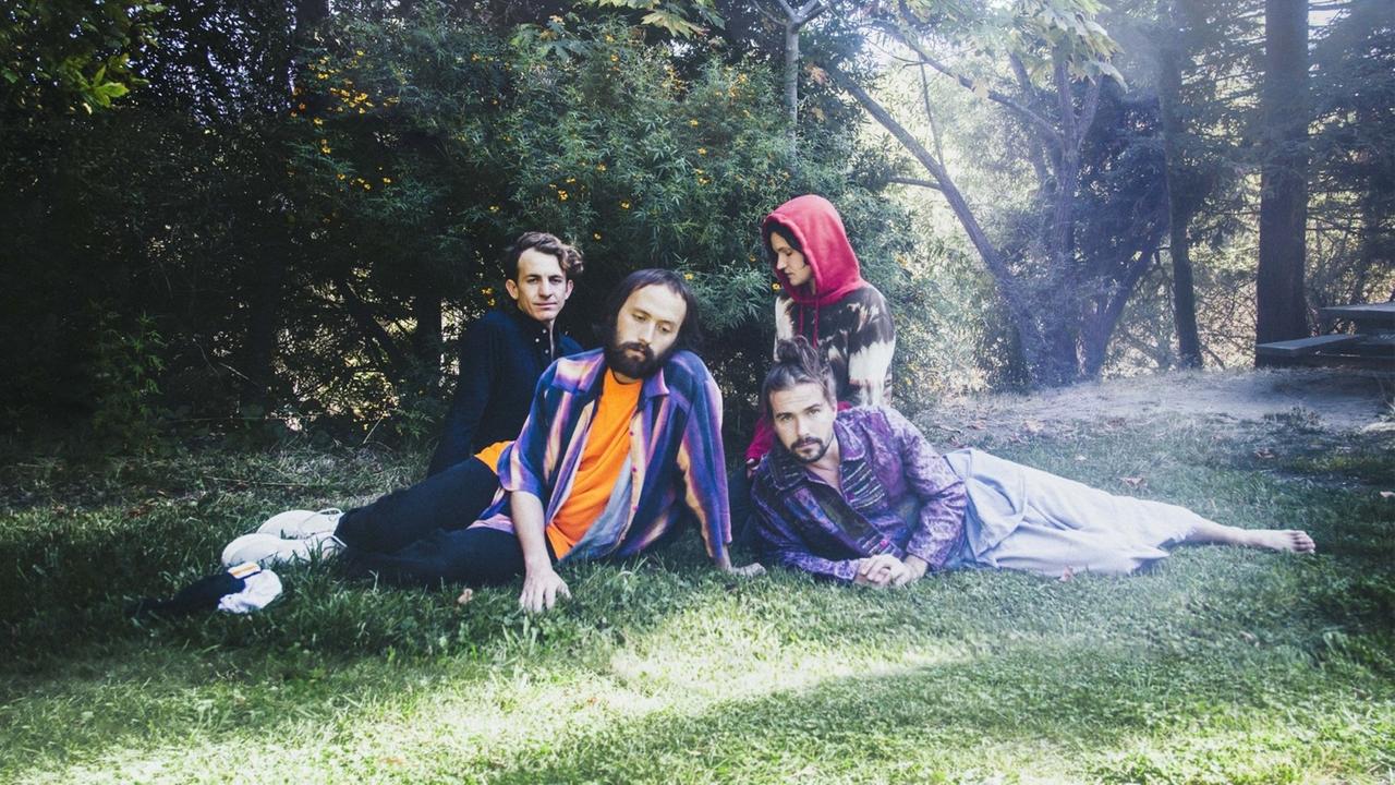 Die Mitglieder der US-amerikanischen Band Big Thief sitzen auf einer Wiese Die Mitglieder der US-amerikanischen Band Big Thief sitzen auf einer Wiese