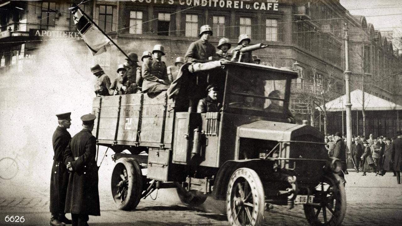 Schwarz-weiß-Foto von 1920: Ein LKW, auf dessen Ladefläche zahlreiche Freikorpssoldaten stehen. Schwarz-weiß-Foto von 1920: Ein LKW, auf dessen Ladefläche zahlreiche Freikorpssoldaten stehen.