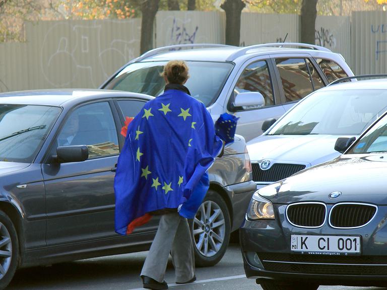 Richtungswahl: Eine junge Frau verteilt Moldau- und EU-Wimpel an Autofahrer im Stadtzentrum von Chisinau.