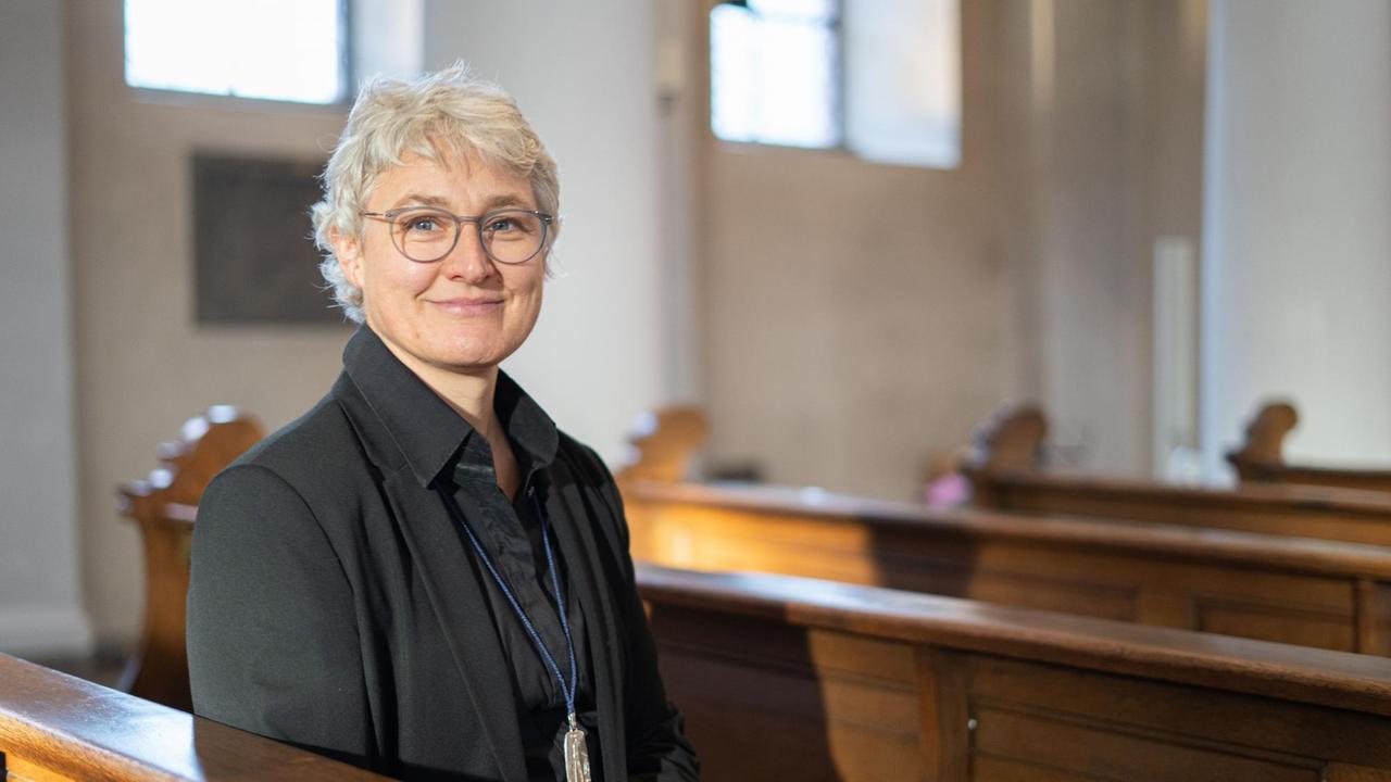Schwester Katharina Ganz sitzt in einer Kirchenbank und blickt freundlich in die Kamera Schwester Katharina Ganz sitzt in einer Kirchenbank und blickt freundlich in die Kamera
