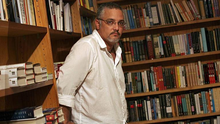 Der kubanische Schriftsteller Enrique del Risco steht vor einer Bücherwand und schaut in die Kamera. Der kubanische Schriftsteller Enrique del Risco steht vor einer Bücherwand und schaut in die Kamera.