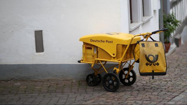 An einer Straßenecke in Idstein (Hessen) steht ein Briefzustellerwagen der Deutschen Post.