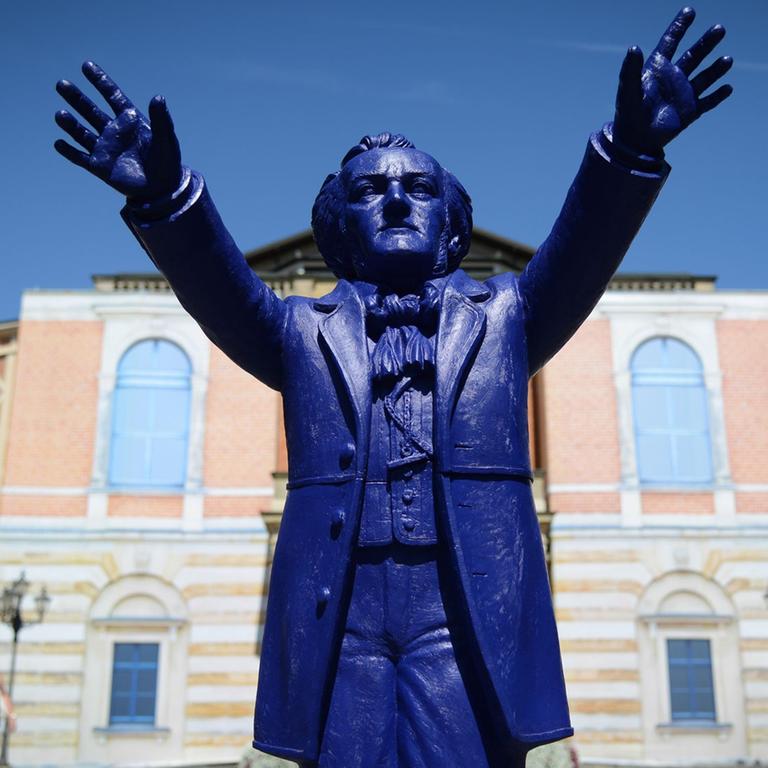 Ein Plastik-Wagner des Künstlers Ottmar Hörl "dirigiert" vor dem Königsportal des Festspielhauses auf dem Grünen Hügel in Bayreuth (Bayern). Ein Plastik-Wagner des Künstlers Ottmar Hörl "dirigiert" vor dem Königsportal des Festspielhauses auf dem Grünen Hügel in Bayreuth (Bayern).