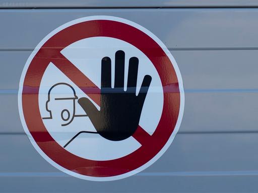 Aufkleber eines unkonventionellen Stopp-Schildes. Zu sehen ist das Piktogramm eines Mann der eine große schwarze Hand nach vorn hält.