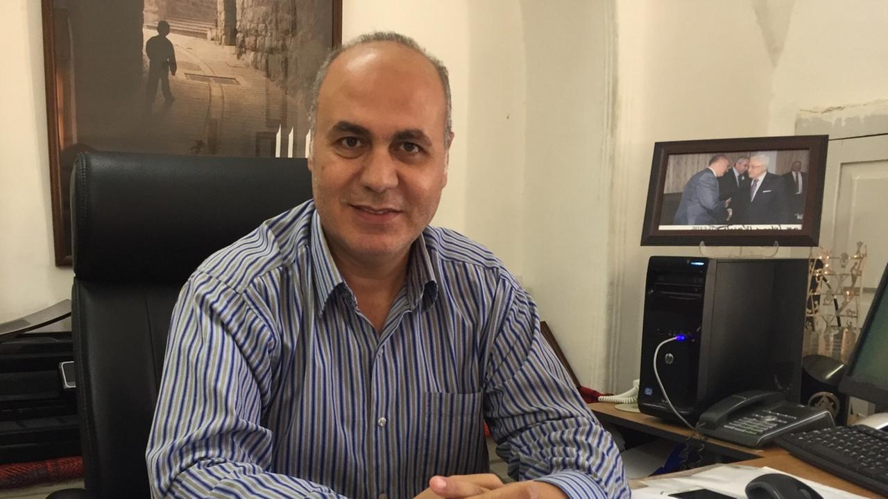 Emad Hamdansitrzt an einem Schreibtisch