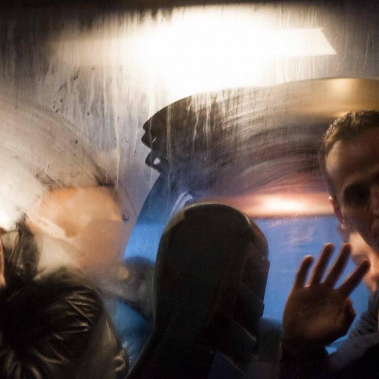 Kosovoalbaner besteigen einen Bus in Pristina, der sie in die EU bringen soll (5.2.2015). Ein junger Mann winkt aus dem Fenster.
