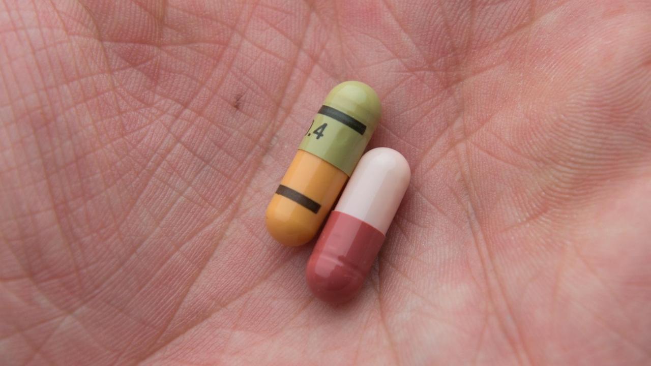 Zwei kleine bunte Pillen in der Innenhand eines Mannes Zwei kleine bunte Pillen in der Innenhand eines Mannes