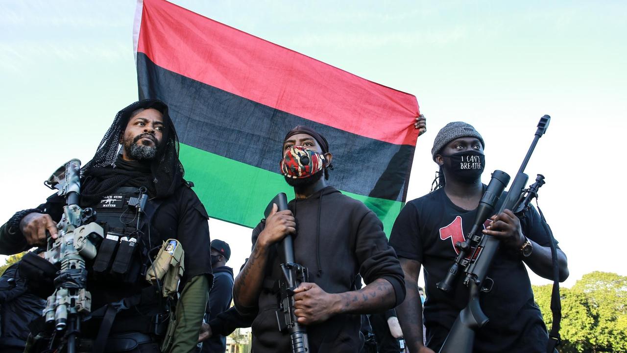 Mitglieder der "Black Rider Liberation Party" tragen Gesichtsmasken und Gewehre auf einer Kundgebung im Irving Park, Portland. Mitglieder der "Black Rider Liberation Party" tragen Gesichtsmasken und Gewehre auf einer Kundgebung im Irving Park, Portland.