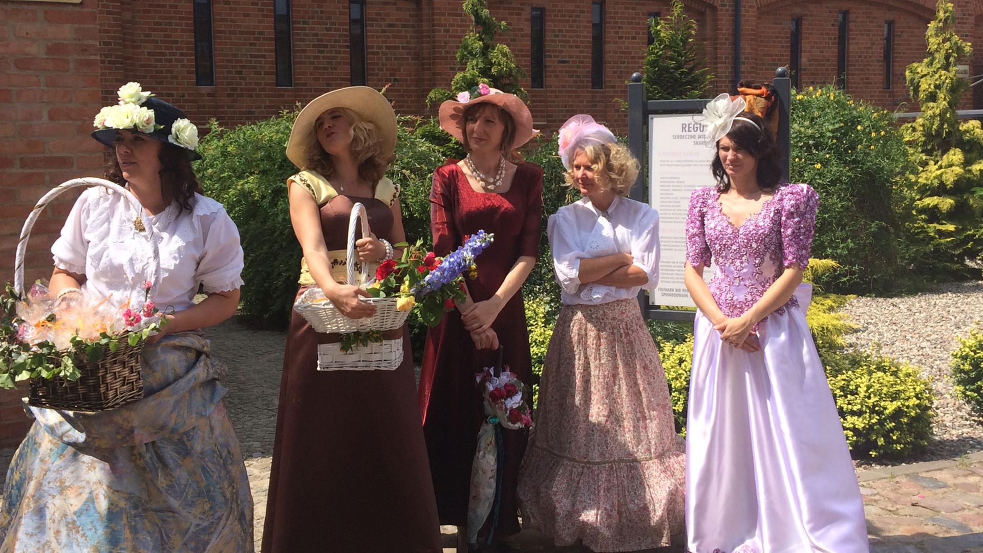 Diese Frauen sind Teil des Umzugs zu Ehren Elisabeths, veranstaltet in dem Dorf, wo sie vor über 100 Jahren gelebt hat – damals Gut Nassenheide in Deutschland, heute Rzedziny in Polen. Mit Kleidern, Hüten und Blumen aus Elizabeths Zeit ziehen sie an den Zuschauern vorbei, Blumenarrangements werden bewundert, es gibt ein Musikprogramm, und Rosen und Kunsthandwerk zu kaufen. Diese Frauen sind Teil des Umzugs zu Ehren Elisabeths, veranstaltet in dem Dorf, wo sie vor über 100 Jahren gelebt hat – damals Gut Nassenheide in Deutschland, heute Rzedziny in Polen. Mit Kleidern, Hüten und Blumen aus Elizabeths Zeit ziehen sie an den Zuschauern vorbei, Blumenarrangements werden bewundert, es gibt ein Musikprogramm, und Rosen und Kunsthandwerk zu kaufen.