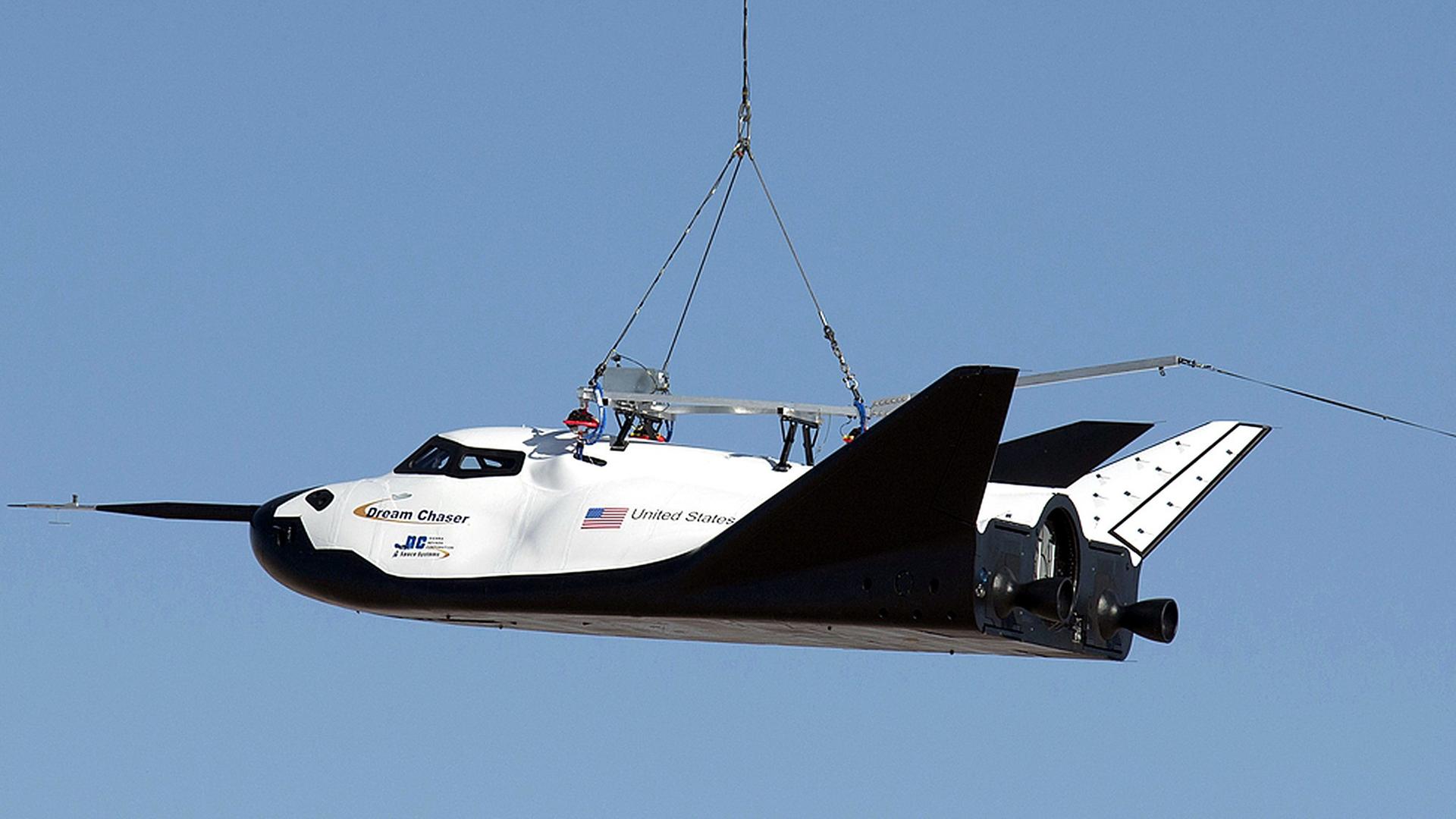 Ein Hubschrauber trägt den Mini-Shuttle Dream Chaser an einem Seil. Ein Hubschrauber trägt den Mini-Shuttle Dream Chaser an einem Seil.