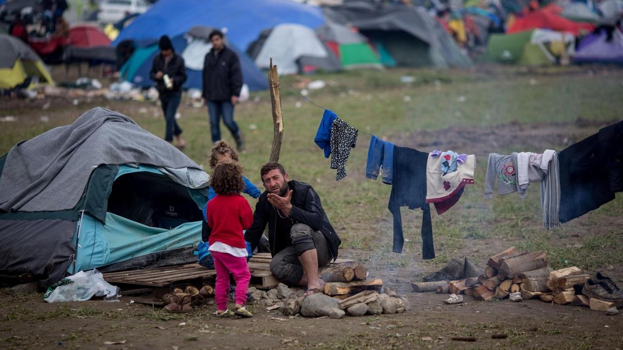 Ein Mann mit zwei Kindern sitzt am 11.03.2016 vor seinem Zelt im Flüchtlingslager in Idomeni an der Grenze zwischen Griechenland und Mazedonien. Ein Mann mit zwei Kindern sitzt am 11.03.2016 vor seinem Zelt im Flüchtlingslager in Idomeni an der Grenze zwischen Griechenland und Mazedonien.