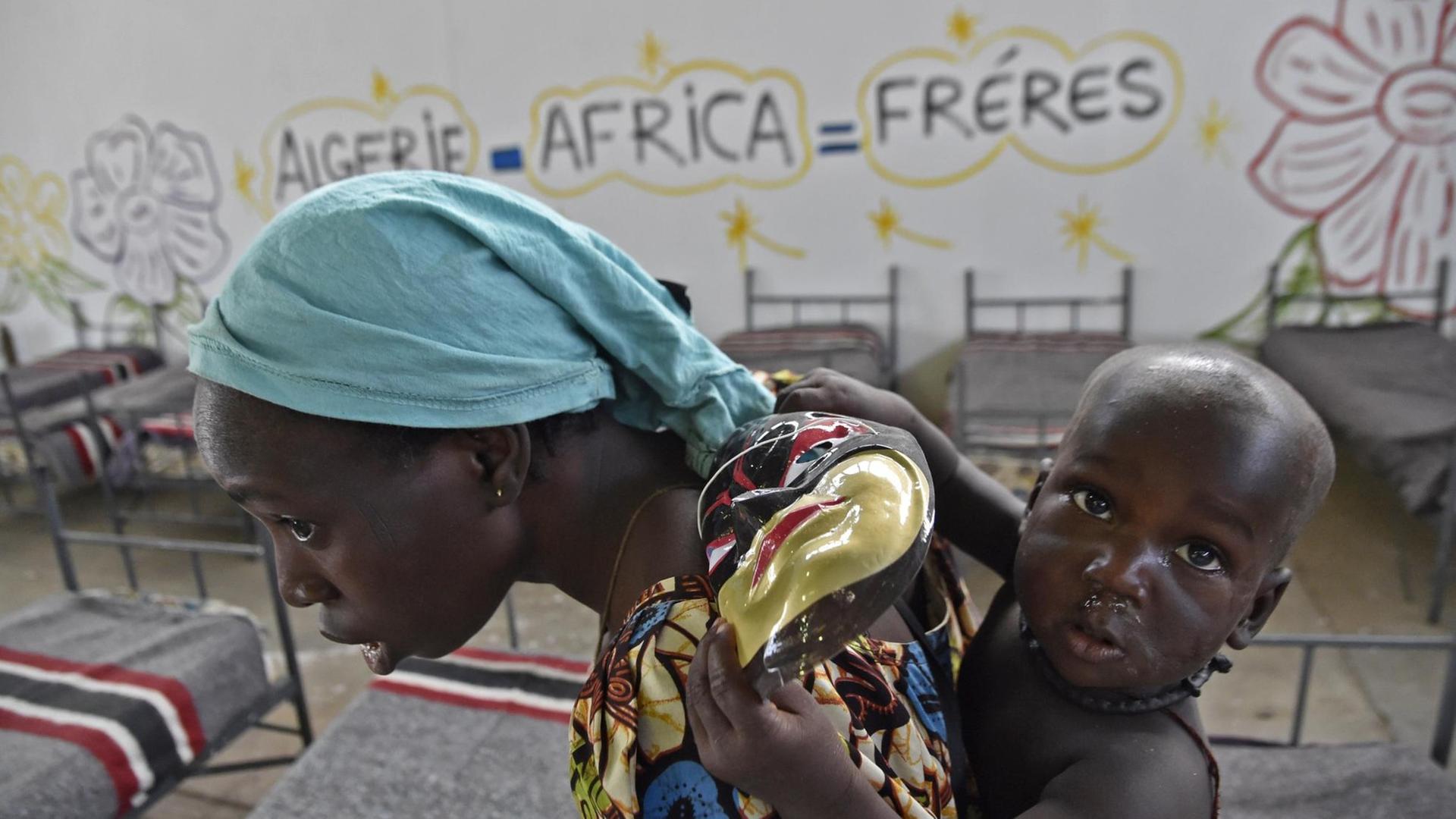 Eine nigrische Migrantin, die illegal nach Algerien eingereist ist, trägt ihr Kind in einem Durchgangslager, als sie am 29. Juni 2018 in Laghouat, Nordalgerien, von algerischen Behörden in den Niger zurückgebracht wird. Eine nigrische Migrantin, die illegal nach Algerien eingereist ist, trägt ihr Kind in einem Durchgangslager, als sie am 29. Juni 2018 in Laghouat, Nordalgerien, von algerischen Behörden in den Niger zurückgebracht wird.