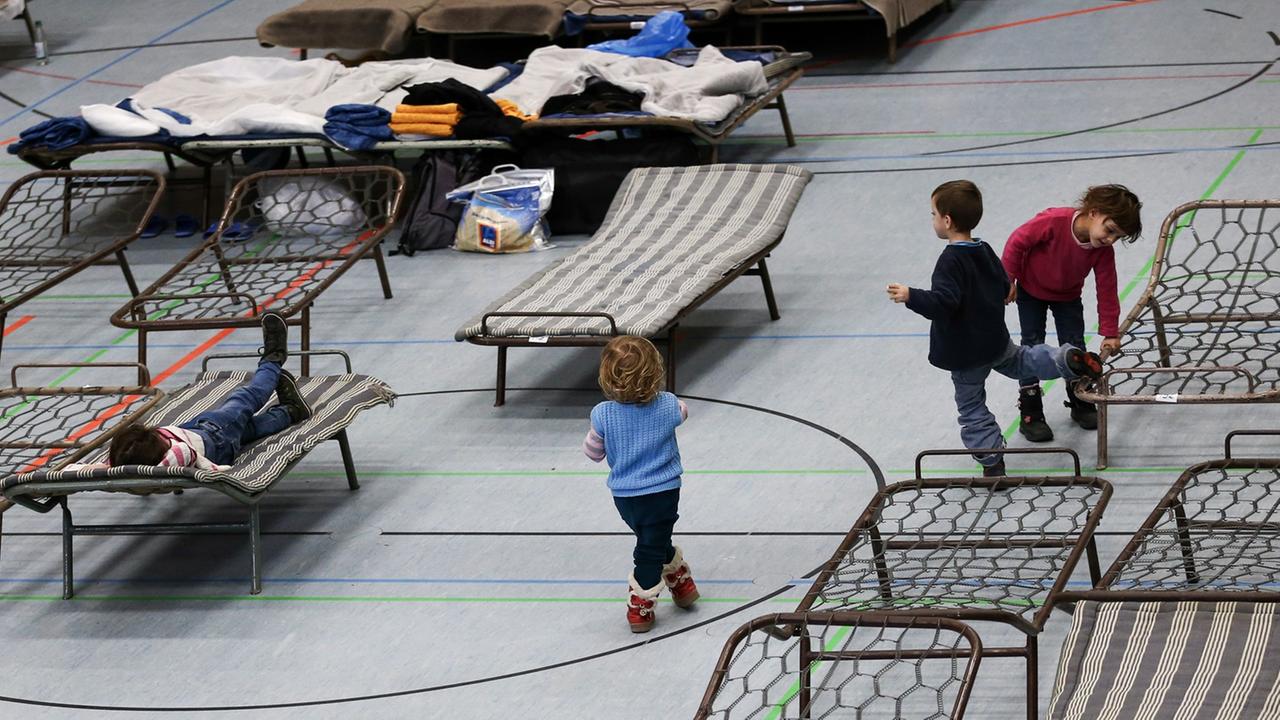 Flüchtlingskinder spielen am 19.02.2015 in der zur Notunterkunft für Asylbewerber umfunktionierten Frankenhalle in Neustadt bei Coburg (Bayern) zwischen den Feldbetten. Flüchtlingskinder spielen am 19.02.2015 in der zur Notunterkunft für Asylbewerber umfunktionierten Frankenhalle in Neustadt bei Coburg (Bayern) zwischen den Feldbetten.