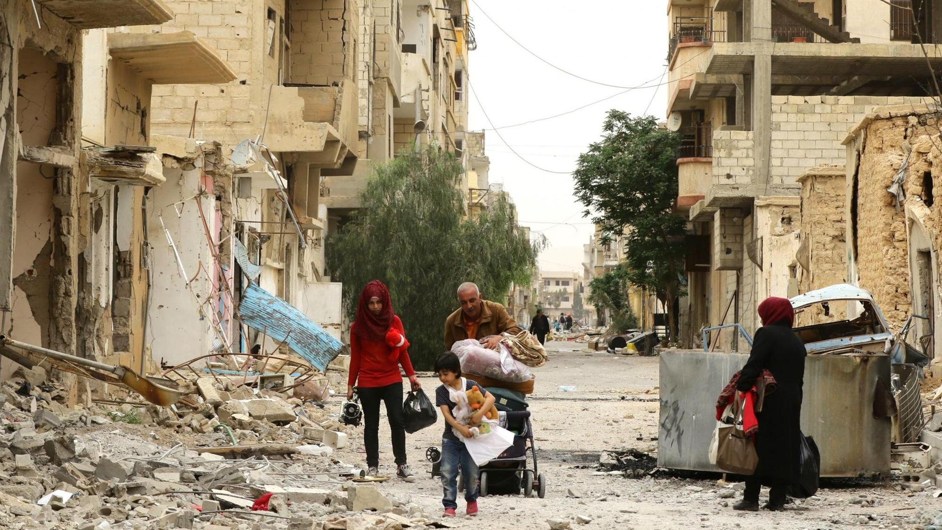 Bewohner der syrischen Stadt Palmyra inspizieren ihre zerstörten Häuser.