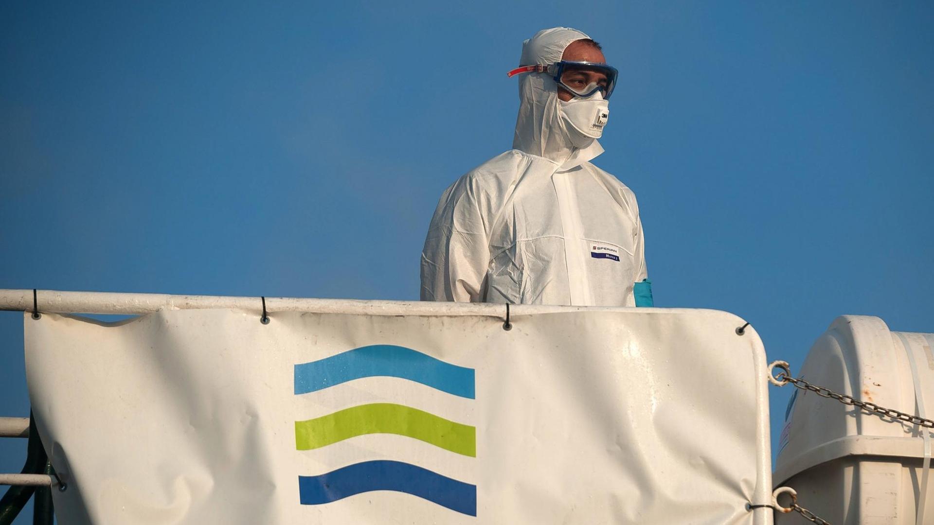 Ein Mann in Schutzkleidung steht am 25. Juli 2020 vor Malaga auf einem Schiff mit Frontex-Fahne Ein Mann in Schutzkleidung steht am 25. Juli 2020 vor Malaga auf einem Schiff mit Frontex-Fahne
