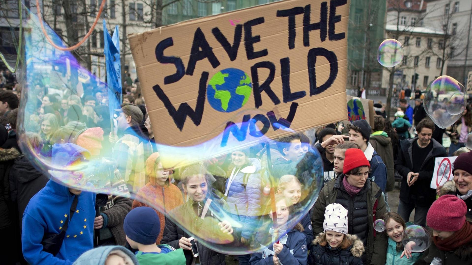 Demonstration von Schülerinnen und Schülern der weltweiten Bewegung "FridaysForFuture"-Bewegung mit Seifenblasen und einem Schild, auf dem "Save The World Now" steht, aufgenommen am 22. März 2019 in Berlin