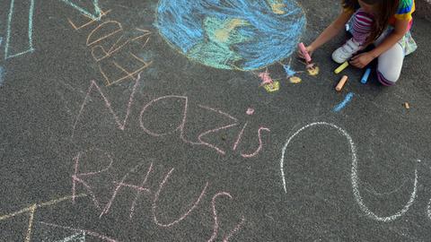Am Rande einer Kundgebung gegen eine Demonstration der Thüringer NPD malt ein Kind mit Kreide in Eisenach Bilder gegen Nazis auf die Straße.