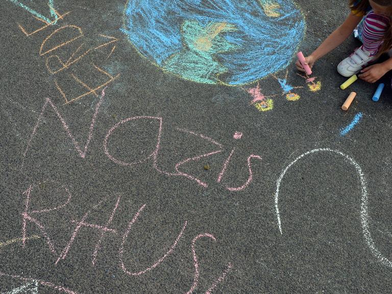 Am Rande einer Kundgebung gegen eine Demonstration der Thüringer NPD malt ein Kind mit Kreide in Eisenach Bilder gegen Nazis auf die Straße.