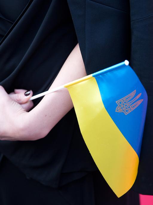 Frau hält eine Ukraine-Fahne in den Händen.